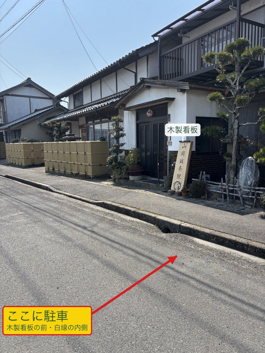 出張所(灘分町)の駐車位置を横から見た写真。木製看板の前の道路側(白線の内側)に駐車